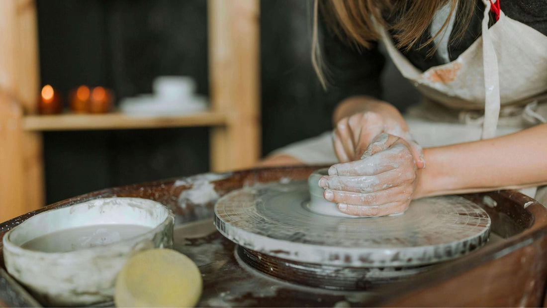 woman throwing small pot on pottery wheel